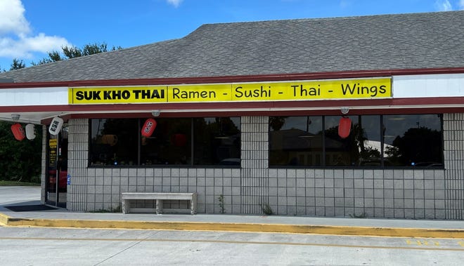The building for a previous business has been transported by Suk Kho Thai into a restaurant with a yellow banner-style sign and red Chinese lanterns.