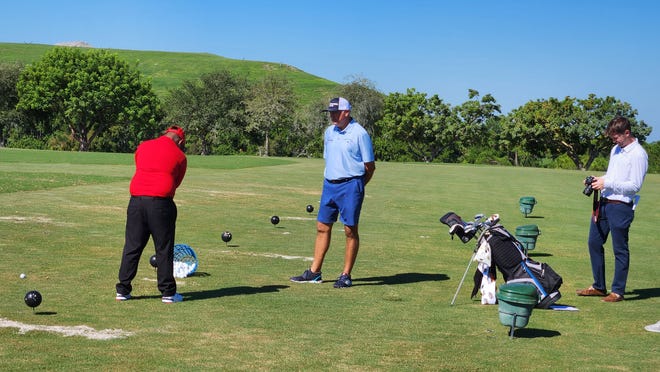 Ken Duke, right, working with First Tee assistant junior coach Davis Lucas on the range Monday at First Tee Palm Beaches.