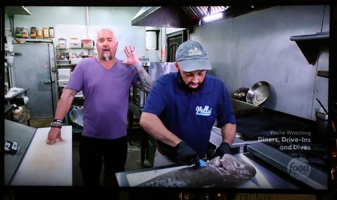 Guy Fieri, host of "Diners, Drive-Ins and Dives," and Millie's Restaurant and Catering owner Chris Chibbaro, seen here preparing fish collars, in an episode that aired Friday, Sept. 16, 2022.