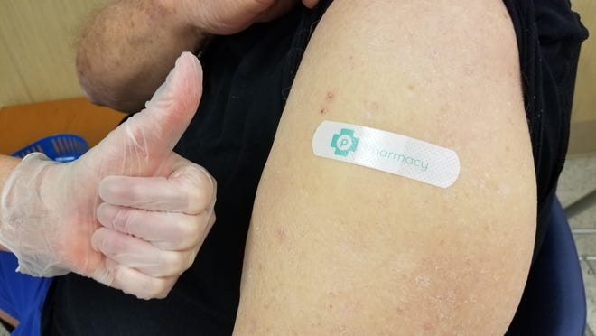 Russell Oxer (right), 78, of Port St. Lucie, Fla., shows where he received the Moderna COVID-19 vaccine at a Publix pharmacy in Palm City, Monday, Jan. 25, 2021, as a staff member gives the thumbs-up. On Jan. 21, select Publix stores in Martin County became the first on the Treasure Coast to administer the vaccine to people 65 and older.