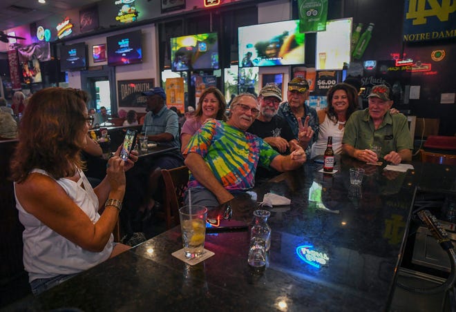 Linda Black (from left) finishes a batch of photos of her veteran friends Krislyn Haves, Kirby Black, Leroy Hohman, Bob Cote, Caroline Cote-York, and Red Simpson, as they have fun socializing at the bar at the St. Lucie Draft House on Wednesday, Aug. 31, 2022, in Port St. Lucie. "Best happy hour, best burger night and best bartenders," said Cote-York, of White City. "Been coming here for years and it's our favorite go-to place for great drinks, great service, and great food."