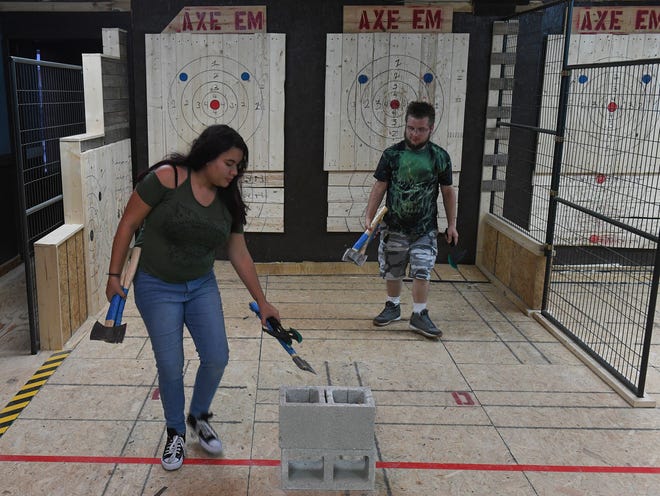 Zadielys Soto, and Raymond Ahmad-Khan, both of Port St. Lucie, prepare to throw another round of axe throwing at Axe Em, a new indoor axe throwing venue in Port St Lucie. Games are played and scored similar to darts, with axes thrown against pine wood targets. "It was very fun," Soto said. "It's a very good stress reliever and a good workout, to be here."