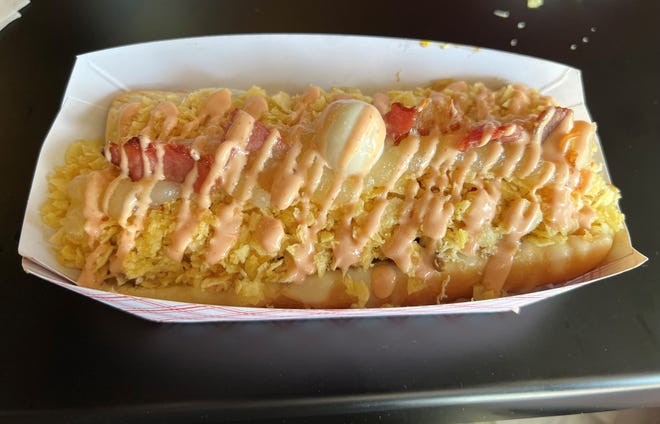 The Gordo Perro with Beef at La Perrada Del Gordo was a hot dog with garlic, pink sauces, pineapple, crushed chips, cheese, bacon, and shredded beef on a bun.