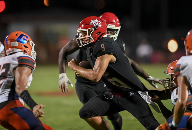 Vero Beach High School quarterback Tylor Aronson (center) is grabbed from behind by a Palm Beach Gardens defender in a 4th quarter play at Billy Living Field in the Citrus Bowl on Friday, Sept. 2, 2022, in Vero Beach. Vero Beach won 34-0.
