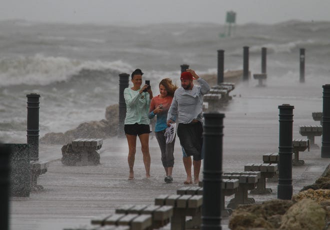 Stephanie Dienemann (from left), her daughter Zoey, 12, and husband Eric, all of Port St. Lucie, bravely walk the Fort Pierce south jetty as the wind and waves ahead of Tropical Storm Nicole churn with the outgoing tide at Jetty Park on Wednesday, Nov. 9, 2022, in Fort Pierce. "Super windy, sand blasting, winds hitting you, it's pretty strong out there, it' fun," Stephanie Dienemann said. "Seventeen years we're here and this is the first time we're going to get the eye."