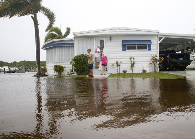 Tom Nolin (left), helps Bob Fischer (middle) and Linda Windows put shutters on their door as the St. Lucie River floods River Drive in the Riverland Mobile Home Park community, Wednesday, Nov. 9, 2022, in Stuart. Tropical Storm Nicole is expected to approach the Treasure Coast as a Category 1 Hurricane bringing tropical storm force winds to the area as it approaches by early afternoon and near or above hurricane force winds overnight, a meteorologist said.