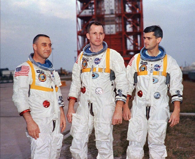 Astronauts Virgil "Gus" Grissom, left, and Roger Chaffee, right, and University of Michigan grad Edward White II pose next to their Saturn 1 launch vehicle on Jan. 17, 1967.