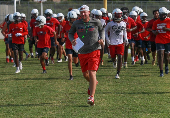 St. Lucie West Centennial High School football coach Josh Watkins, center, leads his team back on to the field after a water break during practice on Monday, Aug. 2, 2021, in Port St. Lucie.