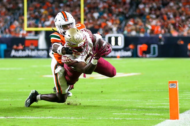 Nov 5, 2022; Miami Gardens, Florida, USA; Florida State Seminoles running back Trey Benson (3) dives into the end zone for a touchdown ahead of Miami Hurricanes cornerback Te'Cory Couch (23) during the second quarter at Hard Rock Stadium. Mandatory Credit: Sam Navarro-USA TODAY Sports
