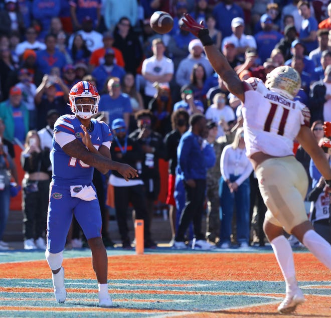 Florida Gators quarterback Anthony Richardson (15) throws the ball over the outstretched hand of Florida State Seminoles defensive end Jermaine Johnson II (11) at Ben Hill Griffin Stadium in Gainesville on Nov. 27, 2021.
