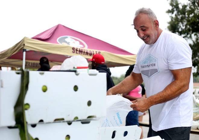 Vinny Marcellino, of Port. St. Lucie, bags donated corn from Belle Glade outside of Sylvia's Flower Patch II on Tuesday, Nov. 22, 2022, in Fort Pierce. Marcellino, who has participated in the turkey giveaway for a few years, owns properties in the Avenue D area. "Everybody needs a little help," Marcellino said while giving back to the community. "I'm heavily invested in Lincoln Park and revitalizing the neighborhood."