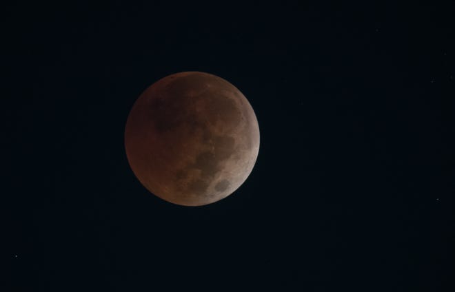 A blood moon is seen during a lunar eclipse minutes before sunrise as it nears totality on Tuesday, Nov. 8, 2022, seen from Port St. Lucie.  The moon passed through the center of the Earth's shadow, occurring only 5.8 days before apogee.