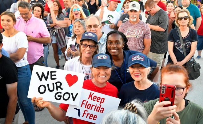 Supporters hold signs backing Florida Gov. Ron DeSantis during Friday everting's rally on the grounds of the American Muscle Car Museum on Sarno Road in Melbourne.
