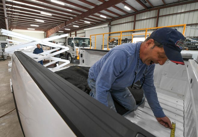 Doug Desmarais, who works in electrical and assembly at Phoenix Metal Products, measures and marks the bed of a Chevrolet HD2500 truck in preparation for the installation of a scissor lift (background) on Wednesday, Feb. 16, 2022, while working inside their warehouse at the Treasure Coast International Airport and Business Park in Fort Pierce. Phoenix Metal Products, a manufacturer of airline ground support equipment, is having difficulty acquiring the new trucks needed to manufacture products for their clients, due to the microchip shortages affecting the automotive industry.
