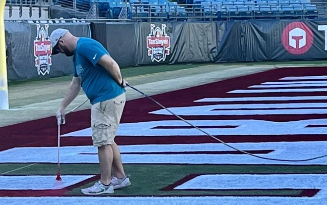 A TIAA Bank Field worker carefully paints South Carolina's colors onto one of the end zones at TIAA Bank Field in preparation for Friday's TaxSlayer Gator Bowl game.