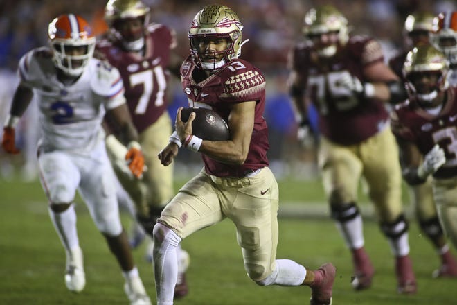 Florida State quarterback Jordan Travis (13), seen here running away from Florida defenders in the fourth quarter, made as many memorable plays with his legs as his right arm in the Seminoles' 45-38 victory last week at Doak Campbell Stadium.