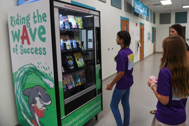 Students line up in Beachland Elementary School's cafeteria to trade in their "surf tickets" for books on Friday, Dec. 9, 2022, in Vero Beach. Beachland's behavior-reward system teaches students how to save, earning gold coins for the book vending machine. "We are really lucky to have a supportive PTA because it takes a team," Beachland's principal Rachel Finnegan said. Not only do the parents help with collecting the books, but they also label them and make sure the students are receiving a book that not only interests them, but also is at their reading level, Finnegan said.