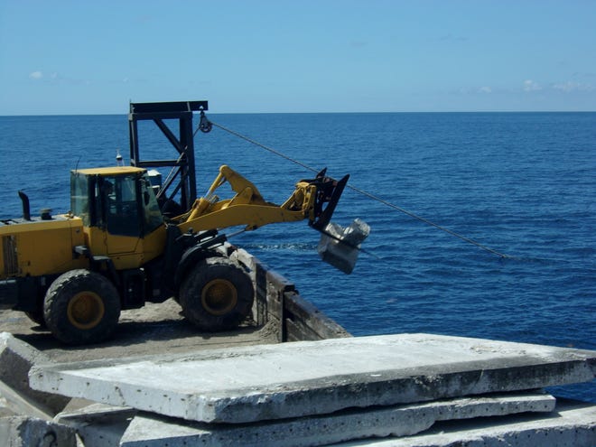 A heavy equipment operator for McCulley Marine Services deploys concrete from an old warehouse at the Port of Fort Pierce originally built by Paul Jacquin & Sons contractors, and then demolished and donated slabs and footers to the reef program.