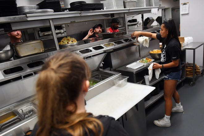 Food runners and wait staff stand in the kitchen of American Icon Brewery in Vero Beach on Wednesday, April 6, 2022, during the early dinner rush. Local restaurants haven't struggled too much in hiring servers, but they are finding it difficult hiring line cooks and dishwashers to fill the need in the kitchen post-pandemic.