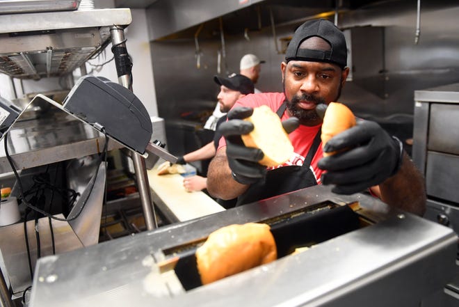 Marvin Jones, assistant chef at American Icon Brewery in Vero Beach, places hamburger buns in the toaster to fill a food order on Wednesday, April 6, 2022. Because of the pandemic, local restaurants are struggling to find line cooks and dishwashers to fill the need in the kitchen.