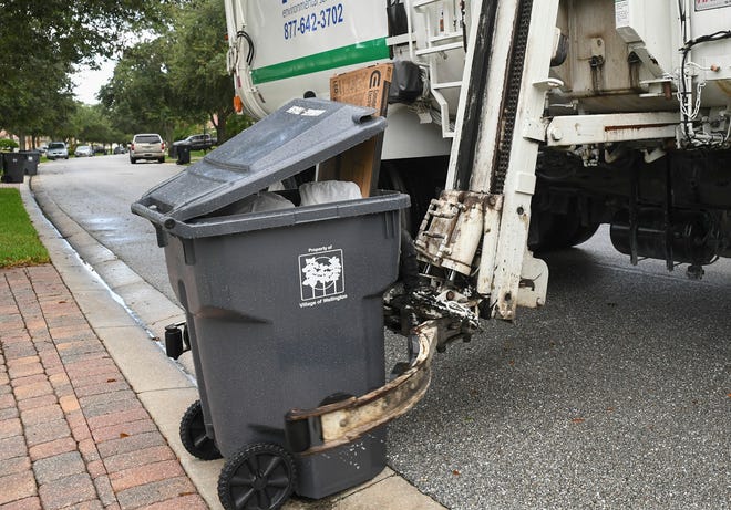 The FCC Environmental Services truck uses a extension arm to grab the designated trash cart placed curbside along Laborie Lane in the VillageWalk community on Monday, Aug. 28, 2022, in Wellington.  The side-loader trucks use an automated system with a video camera for the driver to collect and return the cart curbside.
