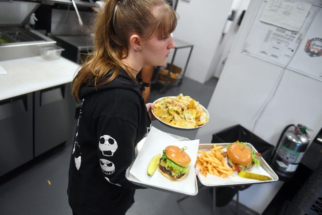 Desarey Legg runs food to the floor on Wednesday, April 6, 2022, during the early dinner rush at American Icon Brewery in Vero Beach. While most restaurants on the Treasure Coast are finding wait staff, the biggest problem post-pandemic is finding line cooks and dishwashers to help in the kitchen.