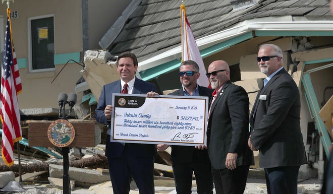 Florida Governor Ron DeSantis hands a multi million dollar check to Volusia County Councilmen Danny Robins, Matt Reinhart and County Manager George Recktenwald, for beach erosion projects, Wednesday January 18, 2023 during a presser on the beach ramp at Dunlawton Avenue and Atlantic Avenue in Daytona Beach Shores.