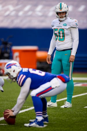 Dolphins long snapper Blake Ferguson watches as brother Reid, the Bills' long snapper, warms up before a game.
