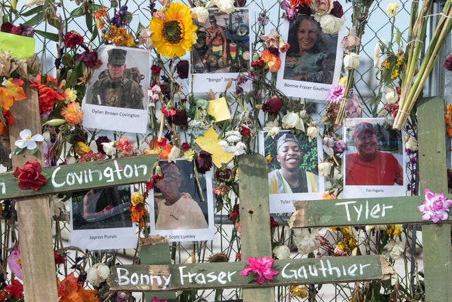 Photographs of Hurricane Ian victims cover a wall of flowers that make up the Hurricane Ian memorial at Centennial Park on Sunday, October 9, 2022 in Fort Myers, Fla. The memorial was started by Leo Soto and the crosses, bearing the victim's names, were added by Roberto Marquez.