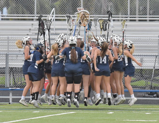 A high school girl's lacrosse team celebrates on the field. A committee of the Florida High School Athletics Association has recommended all female athletes be required to report their menstrual history to their schools when they register to play each year.
