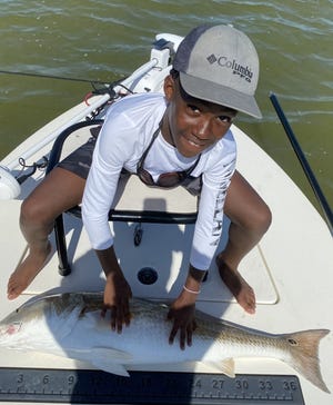 Balin Bolden, 12, shows off the yard-long redfish he caught in Mosquito Lagoon.