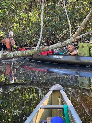 Robert Patch bails his canoe out along the Wood River after a capsize. Joe Hage helped steady the bow as Patch used kayak straps to balance his boat before climbing back aboard.