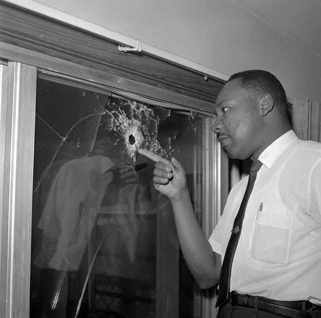 Dr. Martin Luther King points to a bullet hole in a glass sliding door of a home he was scheduled to stay in on Atlantic View in Butler Beach, south of St. Augustine, after it was shot at in 1964.  King was not in the home at the time.