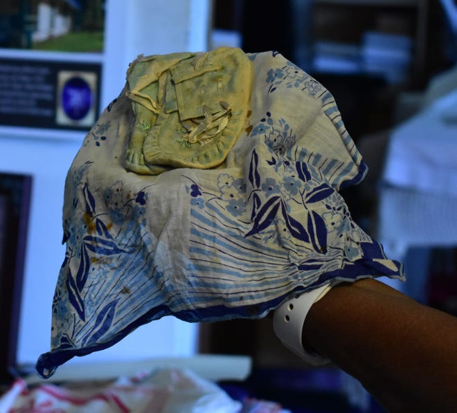 Lizzie Robinson Jenkins unwraps baby shoes that have been stored in the blue handkerchief for 100 years in Archer, Florida on Thursday, Dec. 22, 2022. While she was given the handkerchiefs many years ago, she only recently discovered that there were baby shoes inside.