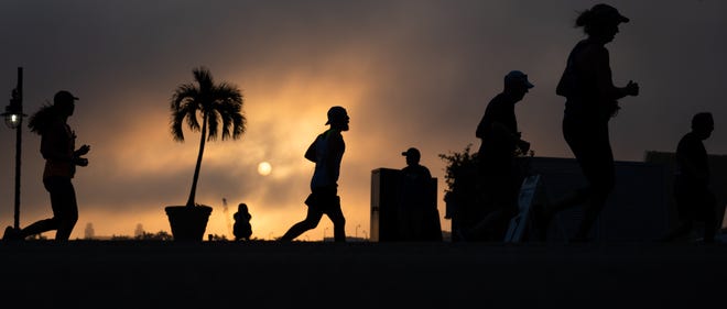 Runners are seen silhouetted against the sunrise on North Flagler Drive during the Garden of Life Palm Beaches Marathon on Sunday, December 11, 2022, in downtown West Palm Beach, FL. Thousands of runners participated in races held over the weekend, which ranged from a 5K all the way to a 26.2 mile-long marathon.