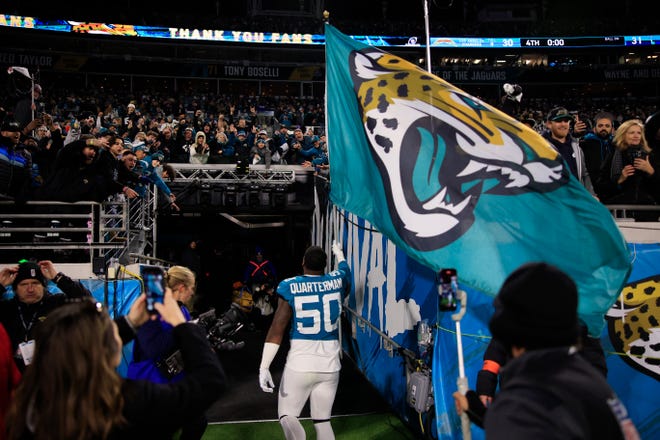 Jacksonville Jaguars linebacker Shaquille Quarterman (50) carries the Jacksonville Jaguars flag into the locker room after the game of an NFL first round playoff football matchup Saturday, Jan. 14, 2023 at TIAA Bank Field in Jacksonville, Fla. The Jacksonville Jaguars edged the Los Angeles Chargers on a field goal 31-30. [Corey Perrine/Florida Times-Union]
