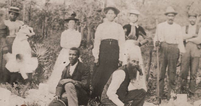 John Henry Monroe (left) and Martine Goins (right) kneel at the funeral of Eli Waldron, Goins' brother-in-law, in 1900 in Rosewood, Florida. Behind them stand Sophie Goins Monroe, her mother and Lydia Goins, the sister of Eli Waldron.
