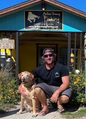 Jamie Thrappas with his yellow lab, Bay, outside his Yellow Dawg bait shop at Highbridge.