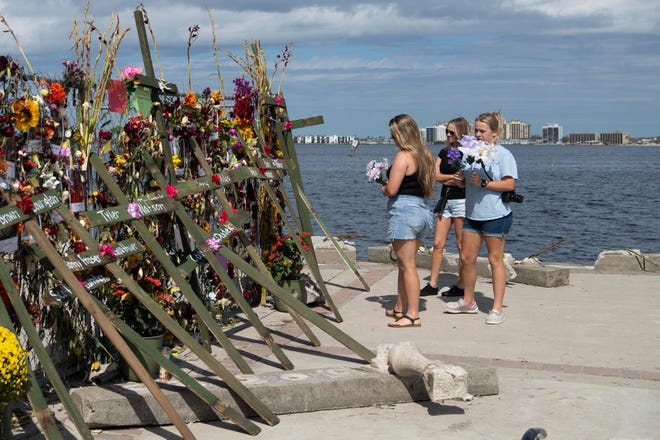 The Challender family, from left, Layni, Dori, and Keylee, brought flowers to place on the Hurricane Ian memorial at Centennial Park on Sunday, October 9, 2022 in Fort Myers, Fla. The memorial was created by Leo Soto and the crosses, bearing the name of the victims, were made and placed there by muralist Roberto Marquez.