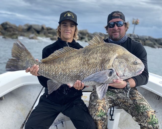 Capt. Jamie Thrappas (right) with a massive black drum he estimated at about 60 pounds.