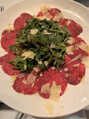 Meating Street Steak & Seafood serves a beef carpaccio with paper thin slices of beef with a heaping pile of peppery arugula and shaved Parmesan.