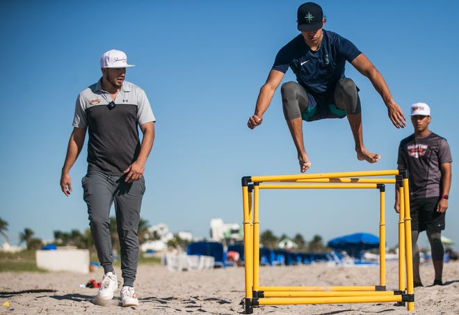 Jeter Rodriguez, a 16-year-old Major League Baseball international free agent from Mexico, enjoys the sunshine Wednesday during a beachside training session as his trainer, Robert Garcia of Showtime Top Velocity Boca Raton, looks on Wednesday in Delray Beach.