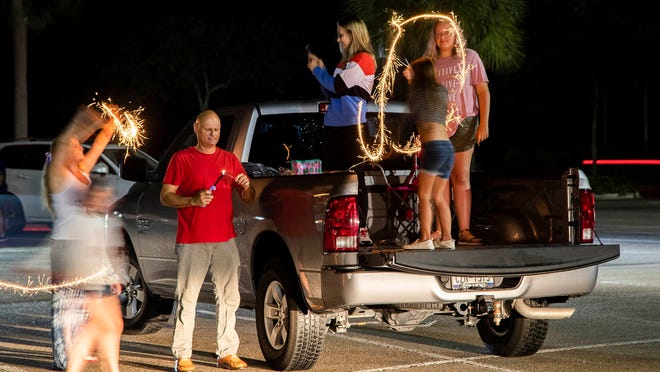 Tim Cable, (center) lights sparklers for family and friends while waiting for fireworks display in Wellington, July 4, 2020