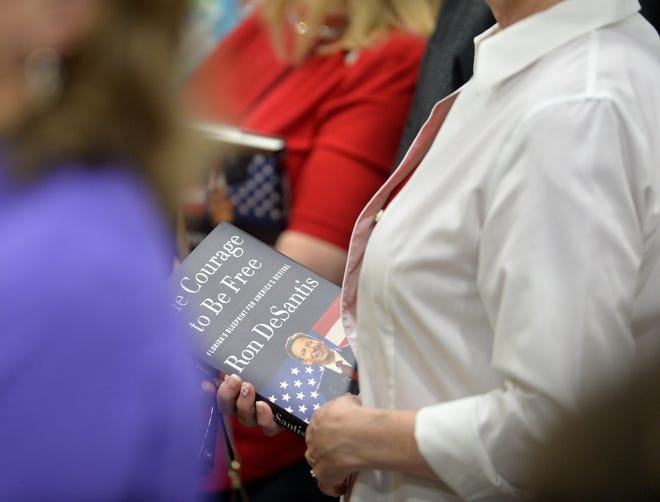 A Gov. Ron DeSantis supporter holds a copy of his new book "The Courage to be Free" during an campaign-style event Tuesday morning at PGT Innovations in Venice.