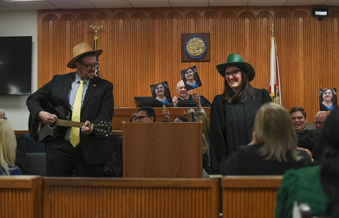 Attorney Jeffrey Battista (left) and Judge Nicole Menz (right) perform a comedy routine as fellow judges wave photos of Leatha Mullins before her swearing in during the Investiture Ceremony for Mullins at the St. Lucie County Courthouse on Friday, Feb.24, 2023, in Fort Pierce.