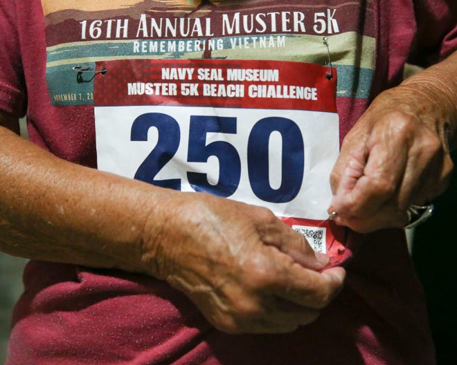 Nicki Campbell, 81, of Stuart, attaches her number to her shirt before participating in the Muster 5K Beach Challenge during the 37th Annual Muster and Music Festival on Saturday, Nov. 5, 2022, at the National Navy UDT-SEAL Museum in Fort Pierce. Campbell has participated in the event seven times and has come in first, second and third in the 70-and-over category.