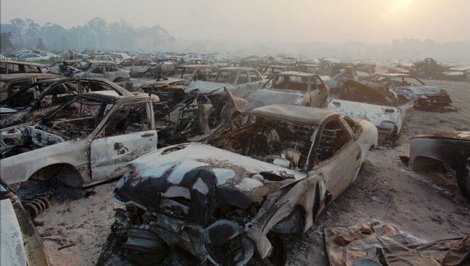 Burned cars litter an auto salvage company in Mims on July 2, 1998. Wildfires forced the evacuation of thousands of people as blazes burned several houses and closed a stretch of Interstate 95. Hundreds of people in and around the towns of Mims and Scottsmoor were again ordered to leave their homes after fires pushed around by shifting winds advanced on their property.