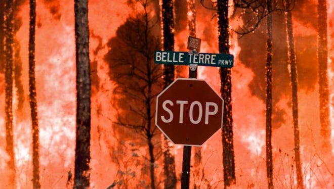 A backfire, set by U.S. Forest Service officials to stop another advancing fire, rages July 3, 1998, in the Indian Trail neighborhood of Palm Coast.