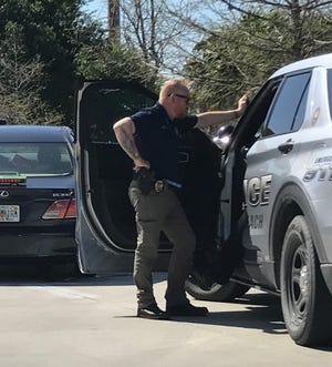 Vero Beach police Detective Lee Evans, talks with an officer inside a patrol vehicle as a car in which a man was found dead was towed away from Sonic on U.S. 1 around 3:45 p.m. Friday March 24, 2023.