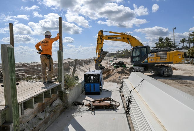 A worker with Shoreline Foundation Inc., of West Park, stands by as an excavator digs to prepare for the installation of sheet piling (bottom right) to create a seawall between the dune and parking lot at Bathtub Reef Beach in Stuart on Thursday, March 9, 2023. The seawall is intended to prevent beach erosion and flooding of the parking lot and MacArthur Boulevard during storms.